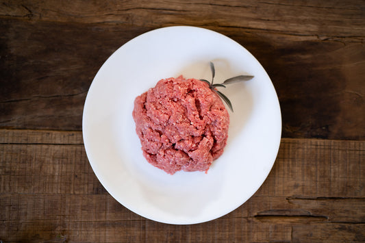 Raw ground meat on a white plate with a wooden background