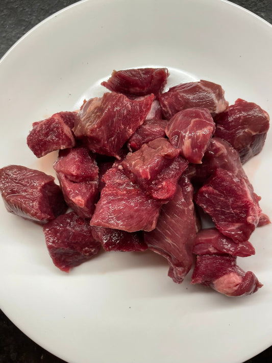 Raw Beef stew meat on a white plate