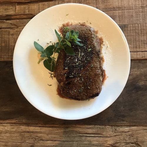 Grilled filet with herbs on a white plate on a wooden table